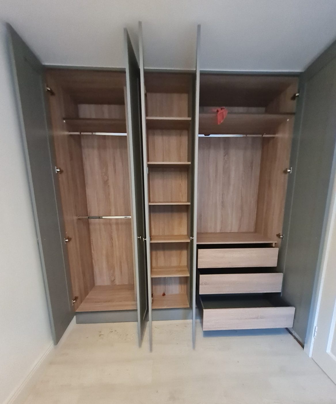Rails, shelves and three drawers behind the grey doors