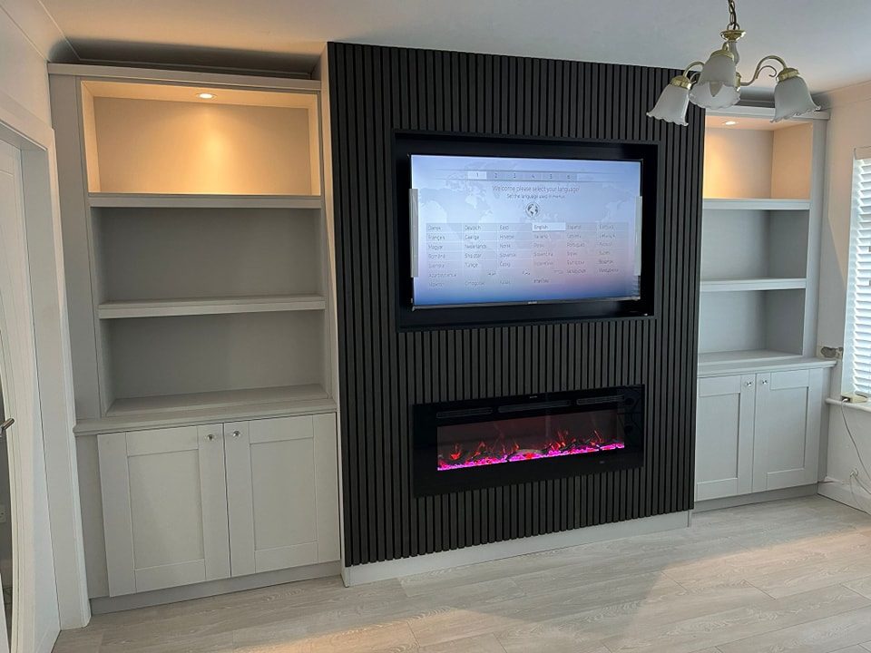 Slatted TV wall with built-in shelving and an electric fire