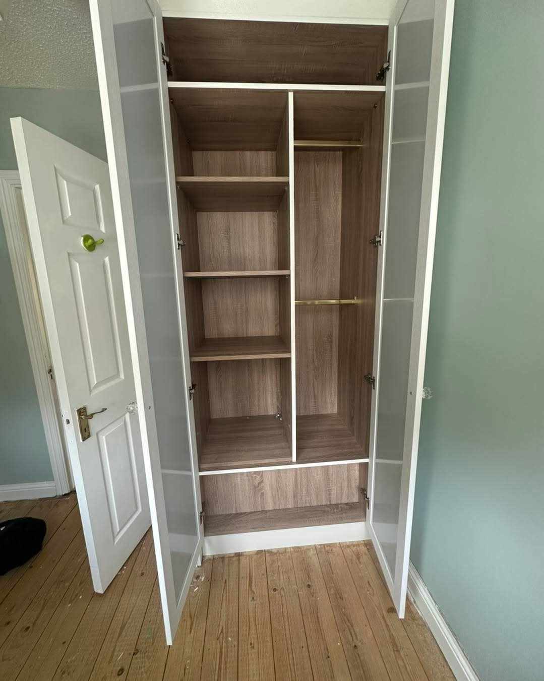Inside a white fitted wardrobe with oak-effect shelves and hanging rail