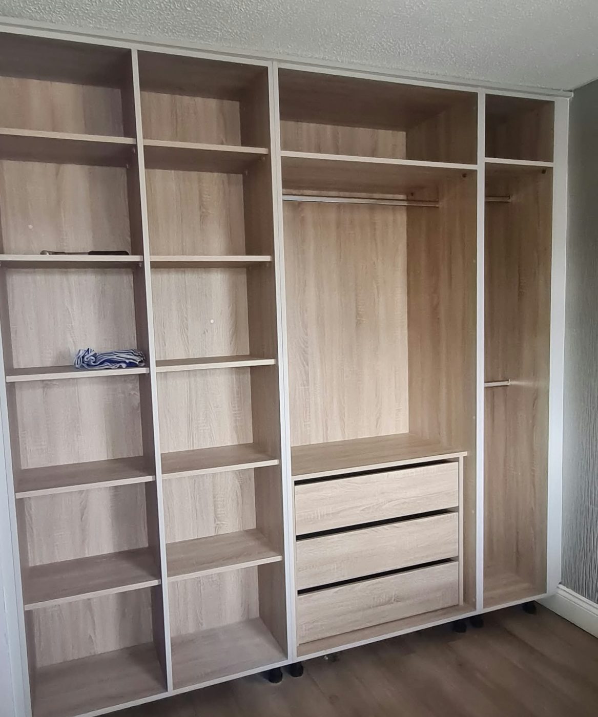 Wall-to-wall wardrobe with oak-effect shelving, rails and drawers