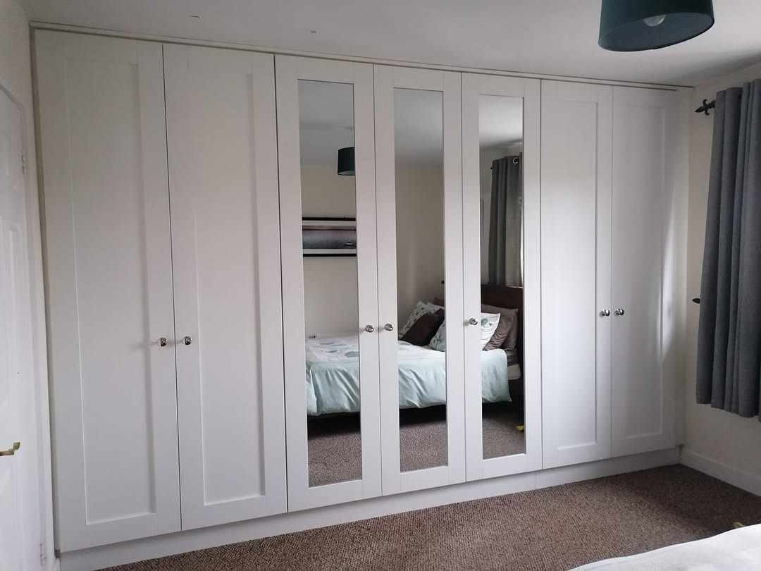 Wall of white shaker wardrobes with mirror doors