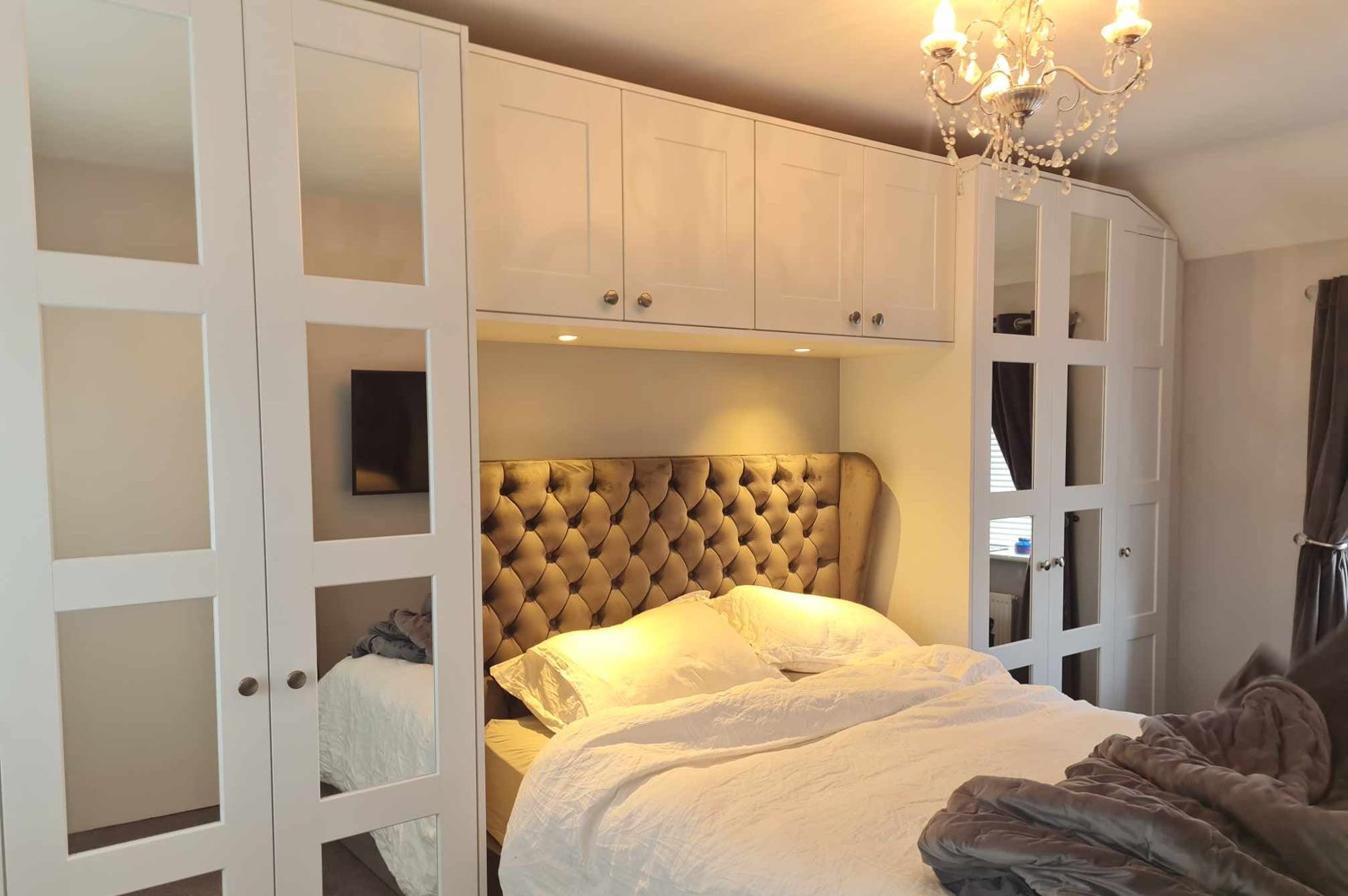 White fitted wardrobes with mirror panels built around a bed in Dublin
